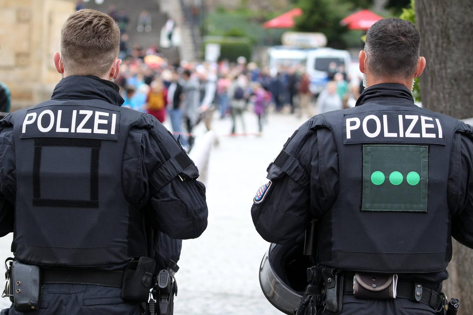 Polizisten stehen in Erfurt mit dem Rücken zur Kamera (Symbolbild): Die Polizei hat Ermittlungen zu einer erneuten offenbar rassistisch motivierten Tat in Erfurt übernommen.