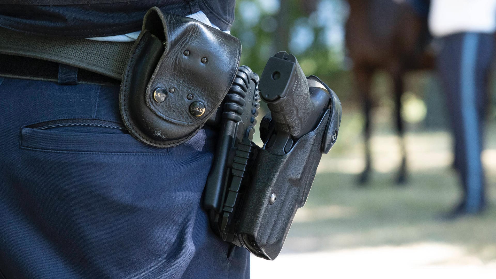 Ein Polizist mit einer Waffe im Halfter (Symbolbild): Nach dem Fund einer toten 15-Jährigen ist ein Verdächtiger festgenommen worden.
