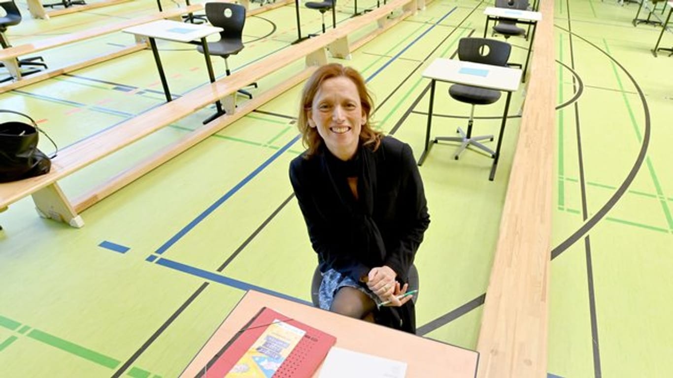 Bildungsministerin Karin Prien sitzt an Schultisch in Turnhalle