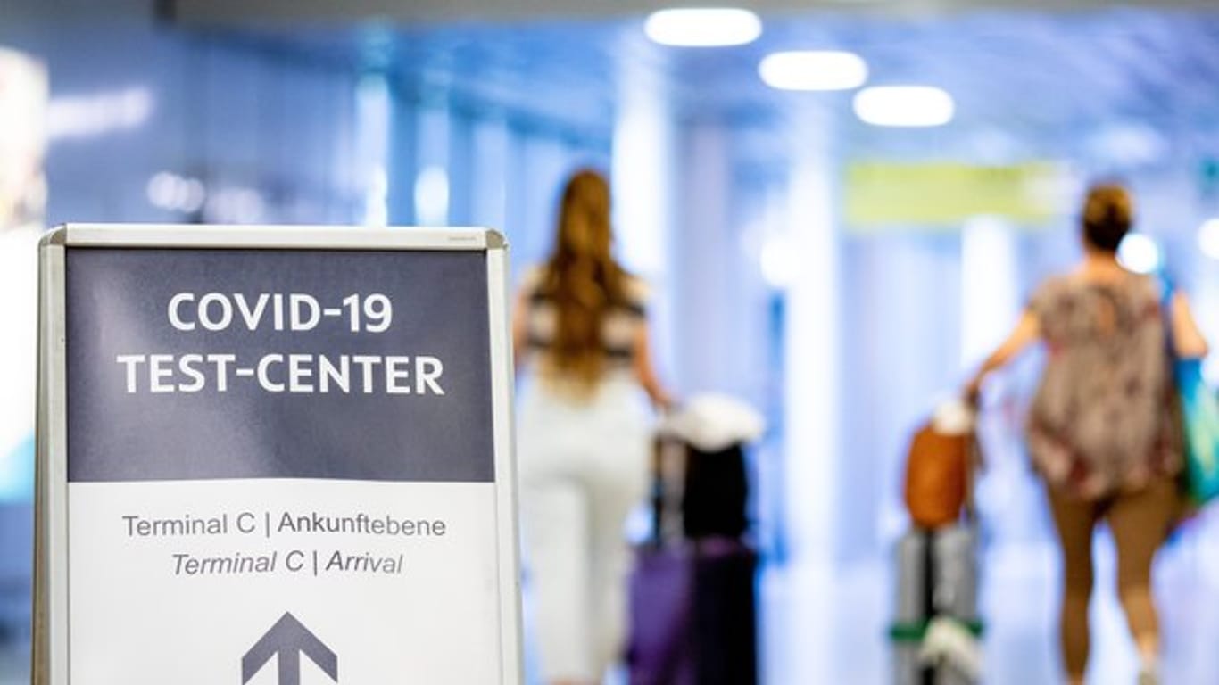 Ein Schild weist Reisende in einem Flughafen auf das Corona-Testzentrum hin.