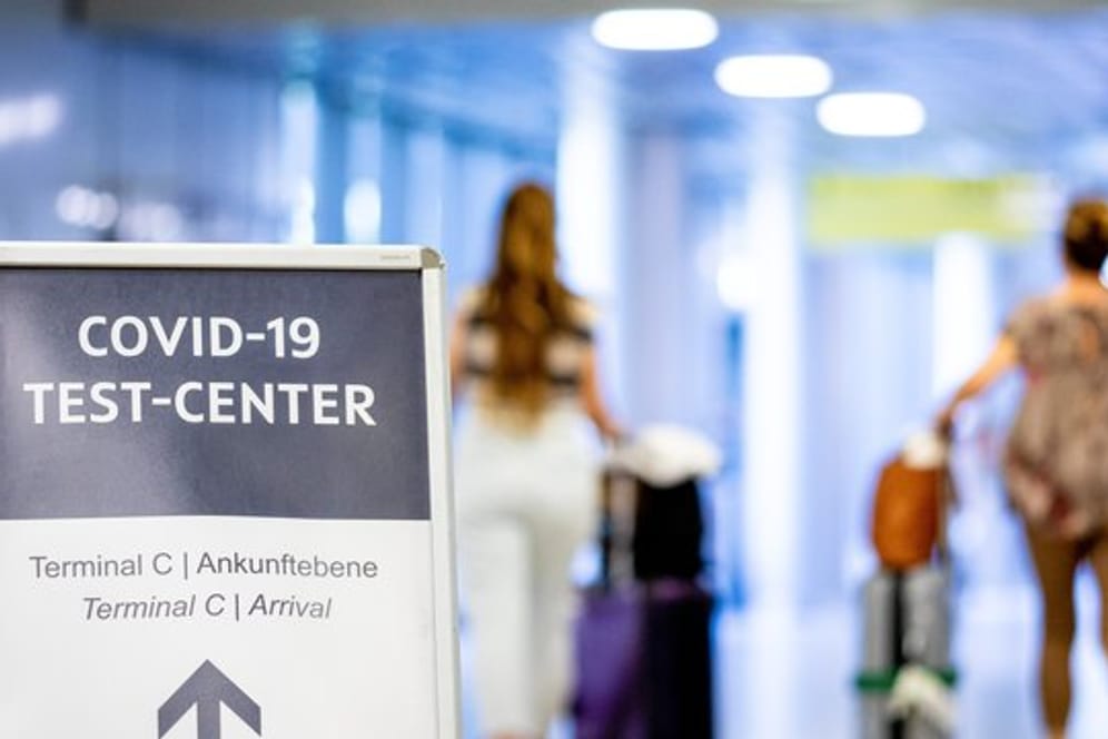 Ein Schild weist Reisende in einem Flughafen auf das Corona-Testzentrum hin.