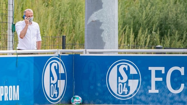 Schalkes Sportvorstand Jochen Schneider steht beim Training hinter einer Bande und telefoniert mit seinem Handy. Schalkes Sportvorstand Jochen Schneider steht beim Training hinter einer Bande und telefoniert mit seinem Handy.