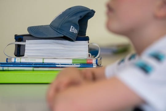 Eine Mund-Nasen-Bedeckung liegt während einer Unterrichtsstunde neben einem Schüler.