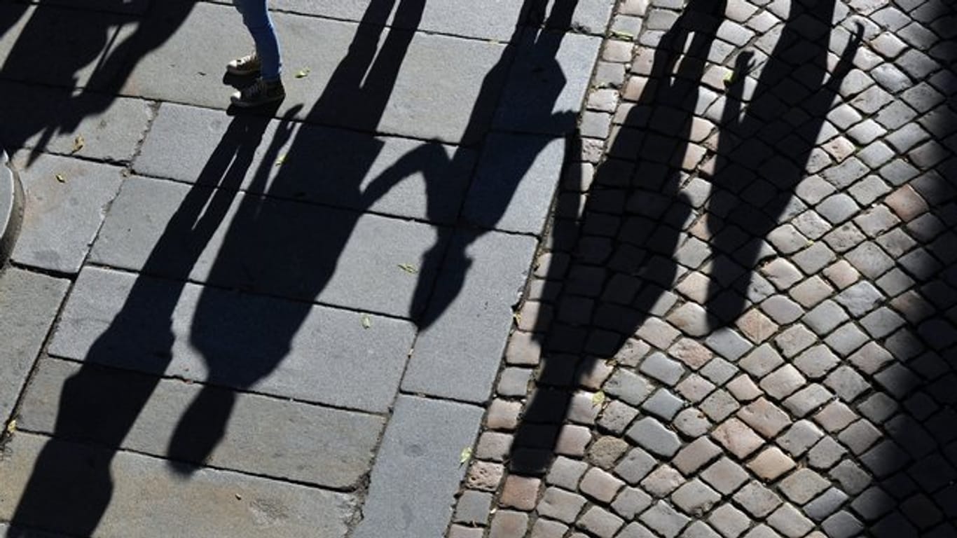 Eine Familie wirft Schatten auf das Pflaster einer Straße.