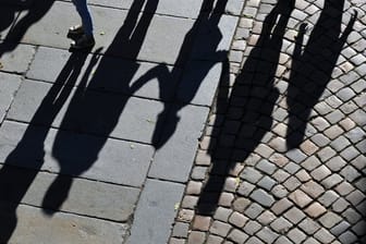 Eine Familie wirft Schatten auf das Pflaster einer Straße.