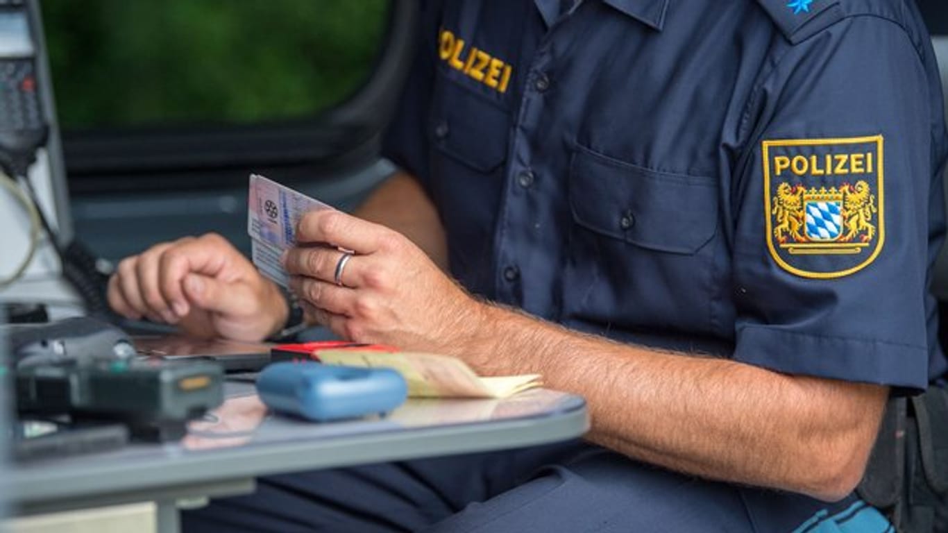 Ein Beamter der bayerischen Grenzpolizei kontrolliert am Grenzübergang Kirchdorf Dokumente von Autofahrern.