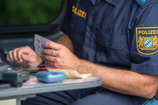 Ein Beamter der bayerischen Grenzpolizei kontrolliert am Grenzübergang Kirchdorf Dokumente von Autofahrern.