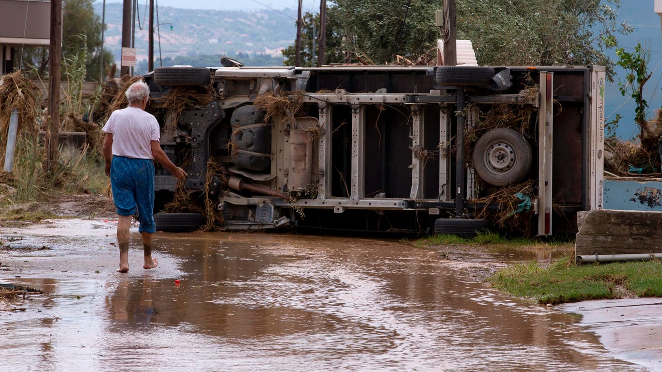 Anwohner vor einem umgekippten Fahrzeug auf der griechischen Insel Evia: Hubschrauber waren im Einsatz, um Menschen von Dächern zu retten.