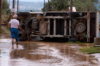 Anwohner vor einem umgekippten Fahrzeug auf der griechischen Insel Evia: Hubschrauber waren im Einsatz, um Menschen von Dächern zu retten.