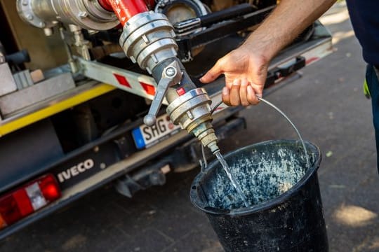 Einsatzkräfte der Freiwilligen Feuerwehr Lauenau zapfen Löschwasser aus dem Tank eines ihrer Einsatzfahrzeuge.