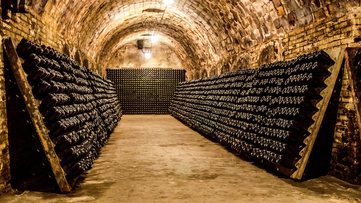 Champagnerflaschen reifen in einem Keller (Symbolbild): In Frankreich gibt es Streit um den Preis für den Schaumwein.