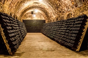 Champagnerflaschen reifen in einem Keller (Symbolbild): In Frankreich gibt es Streit um den Preis für den Schaumwein.