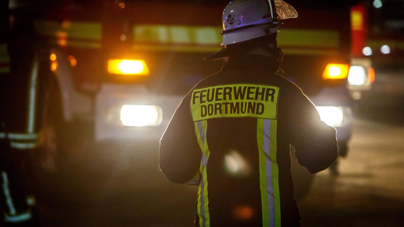 Ein Dortmunder Feuerwehrmann steht vor einem Einsatzfahrzeug (Symbolbild): In Dortmund ist eine Frau bei einem Brand ums Leben gekommen.