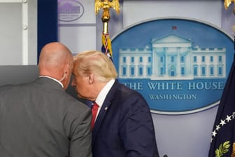 Ein Mitarbeiter des Weißen Hauses flüstert dem US-Präsidenten etwas ins Ohr: Donald Trump hat eine Pressekonferenz abrupt abgebrochen.