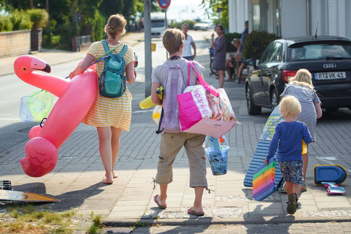 Badegäste in Schleswig-Holstein auf dem Weg zum Strand: Statt ins Ausland zu reisen, machen Millionen Deutsche in diesem Jahr Urlaub in der Heimat.