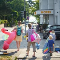 Badegäste in Schleswig-Holstein auf dem Weg zum Strand: Statt ins Ausland zu reisen, machen Millionen Deutsche in diesem Jahr Urlaub in der Heimat.