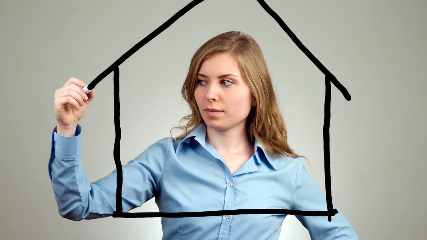 Eine Frau zeichnet ein Haus auf eine Scheibe (Symbolbild): Mit einem Bausparvertrag können Sie eine Immobilie finanzieren.