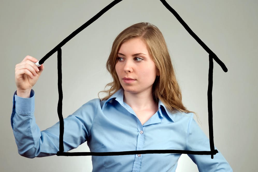 Eine Frau zeichnet ein Haus auf eine Scheibe (Symbolbild): Mit einem Bausparvertrag können Sie eine Immobilie finanzieren.