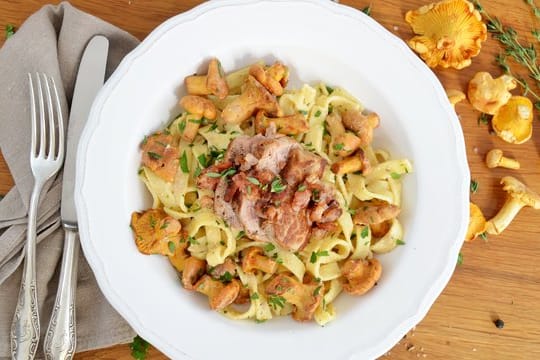 Pfifferlinge werden hier zusammen mit Tagliatelle, Schweinefilet und Bacon serviert.