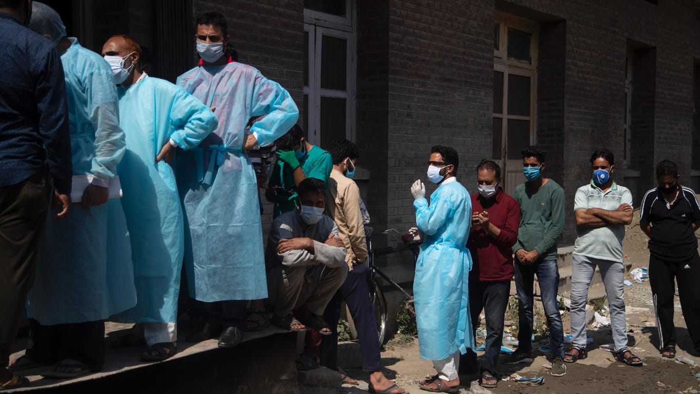 Angehörige und deren Begleiter warten im indischen Srinagar vor einem Krankenhaus, um Sauerstoffflaschen für die Versorgung von Covid-19-Patienten abzuholen.
