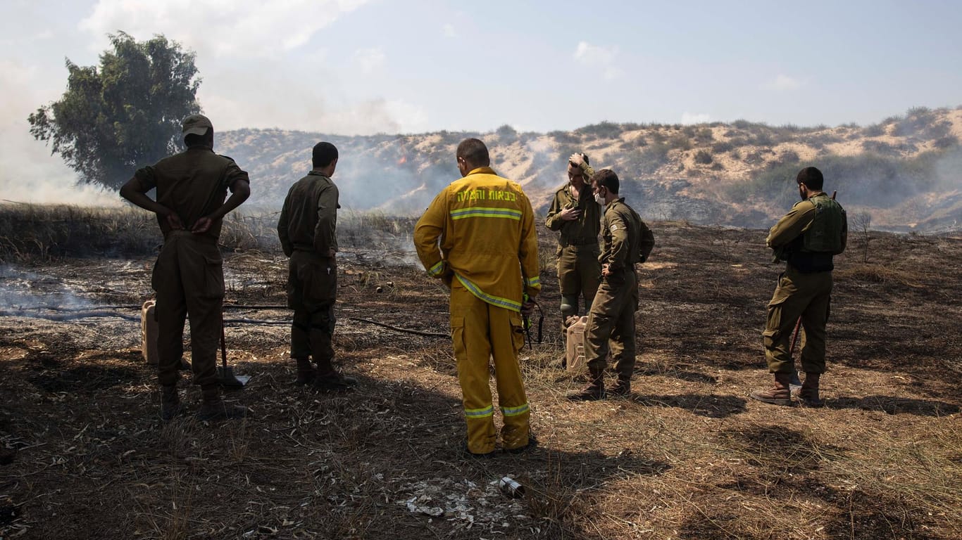 Soldaten und Einsatzkräfte der Feuerwehr löschen Brände, die bei Angriffen aus dem Gaza-Streifen ausgelöst wurden.