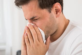 Ein Mann putzt sich die Nase: In Corona-Zeiten sollte man beim Niesen besonders achtsam sein.