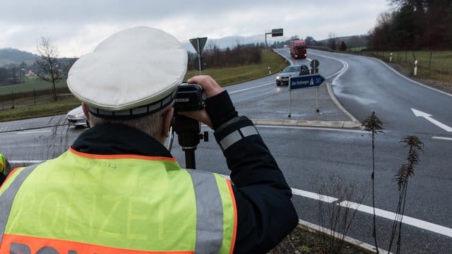 Ein Polizist misst die Geschwindigkeit passierender Autos.