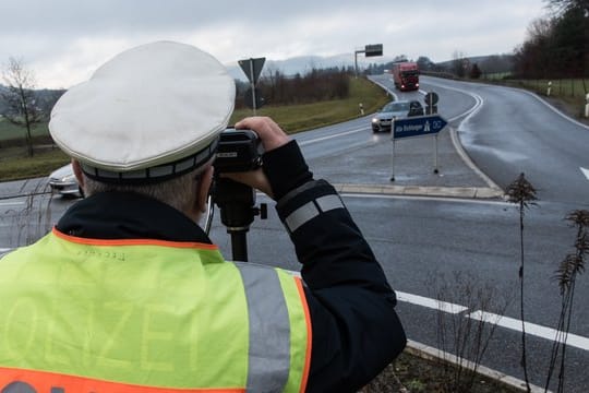 Ein Polizist misst die Geschwindigkeit passierender Autos.