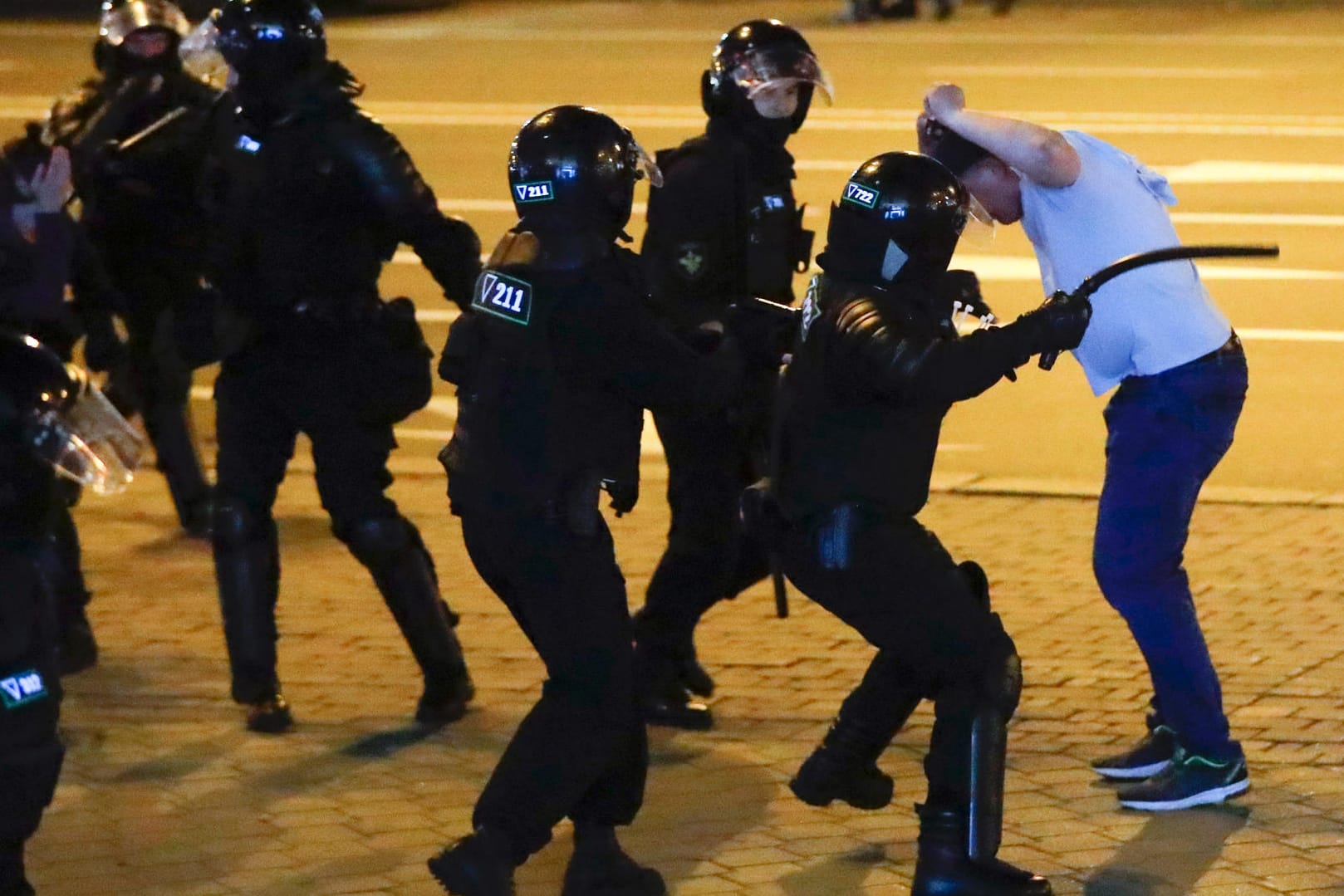 Proteste in Minsk: Polizisten attackieren einen Demonstranten, einer von ihnen holt zum Schlag mit einem Schlagstock aus.