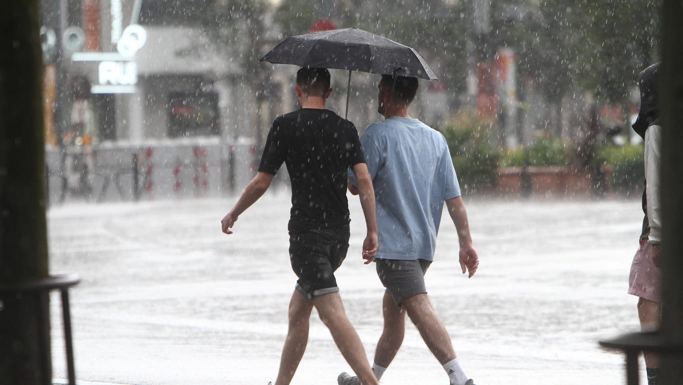 Zwei Männer spazieren mit Regenschirm: Gewitter sind an diesem Wochenende vereinzelt möglich.