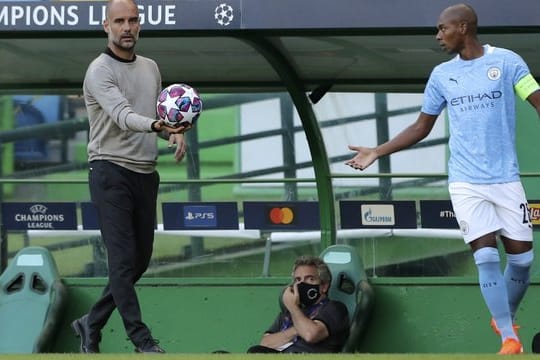 Manchester Citys Trainer Pep Guardiola (l) übergibt den Ball zur Ausführung eines Einwurfes an Fernandinho.