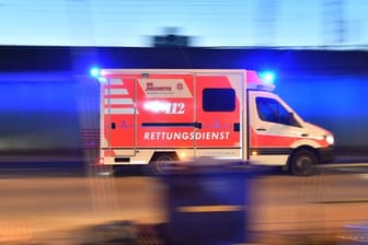 Ein Rettungswagen fährt mit Blaulicht über eine Straße: Ein Kontrolleur wurde in einem ICE mit einem Messer attackiert.
