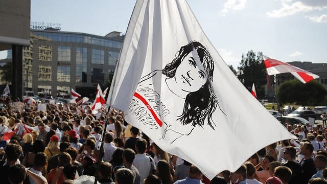 Ein Demonstrant schwenkt bei einem Protest gegen Präsident Lukaschenko eine Flagge mit dem Gesicht der Präsidentschaftskandidatin Tichanowskaja. Ein Demonstrant schwenkt bei einem Protest gegen Präsident Lukaschenko eine Flagge mit dem Gesicht der Präsidentschaftskandidatin Tichanowskaja.