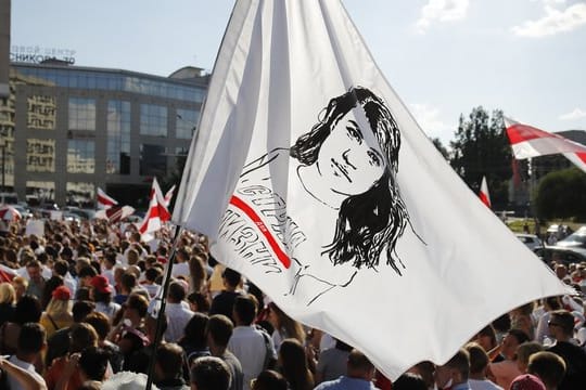 Ein Demonstrant schwenkt bei einem Protest gegen Präsident Lukaschenko eine Flagge mit dem Gesicht der Präsidentschaftskandidatin Tichanowskaja.