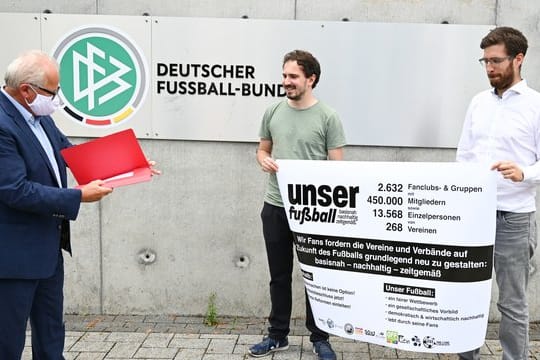 Jan-Henrik Gruszecki (r) und Manuel Gaber (M) von der Fan-Initiative "Unser Fußball" übergeben eine Erklärung zur geforderten Reform an DFB-Präsident Fritz Keller.