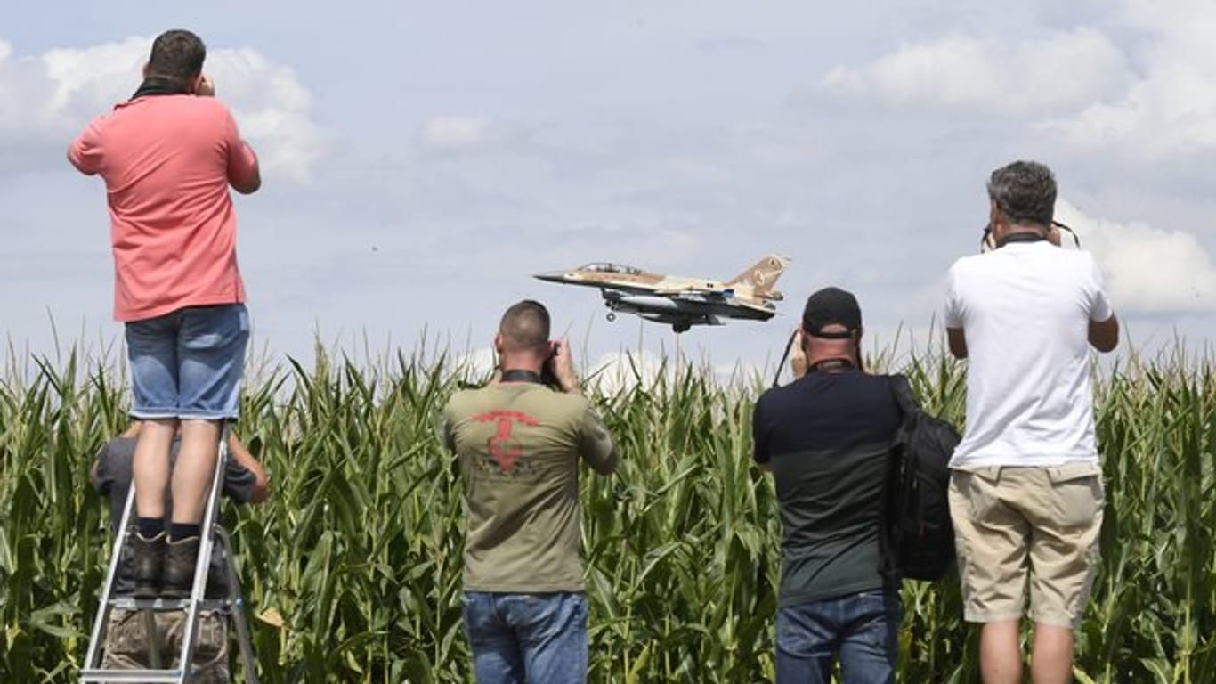 Ein israelischer F-16 Bomber landet auf dem Fliegerhorst Nörvenich im Kreis Düren, beobachtet von mehreren Männern mit Kameras, die an einem Maisfeld stehen.