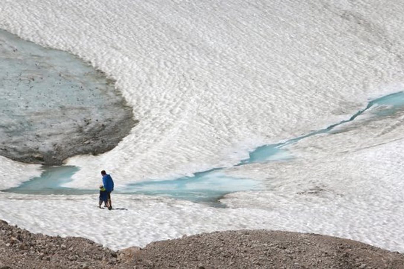 Zwei Wanderer gehen über den Schneeferner-Gletscher auf der Zugspitze.