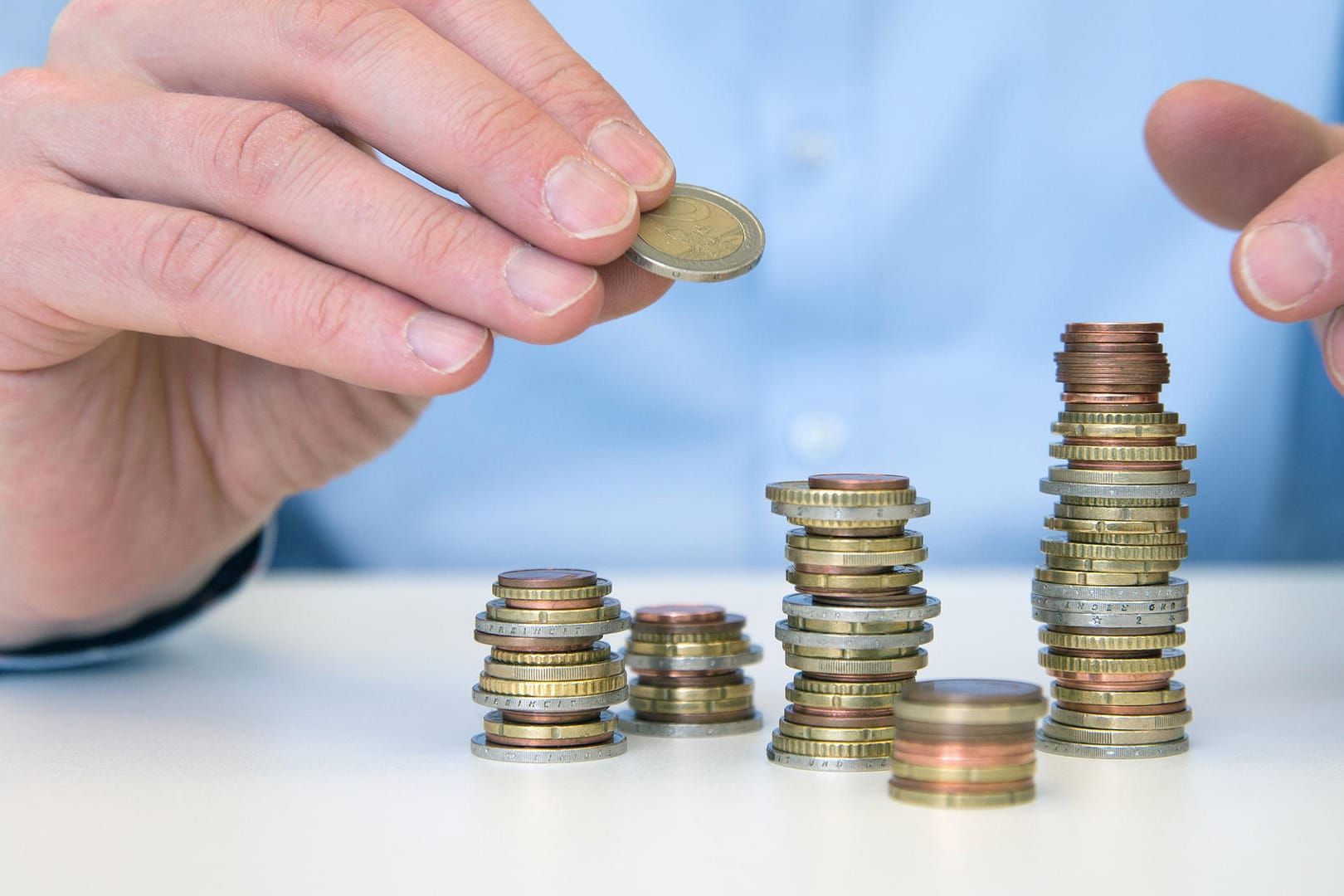 Ein Mann stapelt Münzen (Symbolbild): Eigentlich werden Zinsen jährlich gutgeschrieben. Doch einige Banken gehen anders vor, um Geld zu sparen. Ein Mann stapelt Münzen (Symbolbild): Eigentlich werden Zinsen jährlich gutgeschrieben. Doch einige Banken gehen anders vor, um Geld zu sparen.