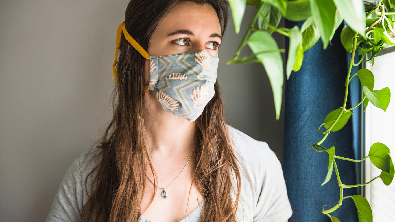 Frau mit Mund-Nasen-Bedeckung: Im Herbst wird in vielen Räumen weniger gelüftet. Die Viruskonzentration kann daher ansteigen.