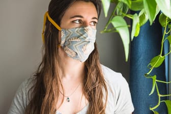 Frau mit Mund-Nasen-Bedeckung: Im Herbst wird in vielen Räumen weniger gelüftet. Die Viruskonzentration kann daher ansteigen.