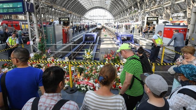 Passanten stehen 2019 im Frankfurter Hauptbahnhof vor Blumen, Kuscheltieren und Beileidsbekundungen. Passanten stehen 2019 im Frankfurter Hauptbahnhof vor Blumen, Kuscheltieren und Beileidsbekundungen.
