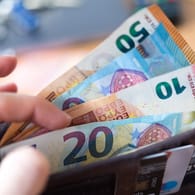 Geldscheine in einem Portemonnaie (Symbolbild): Forscher untersuchen, wie ein bedingungsloses Grundeinkommen den Alltag der Deutschen verändert.