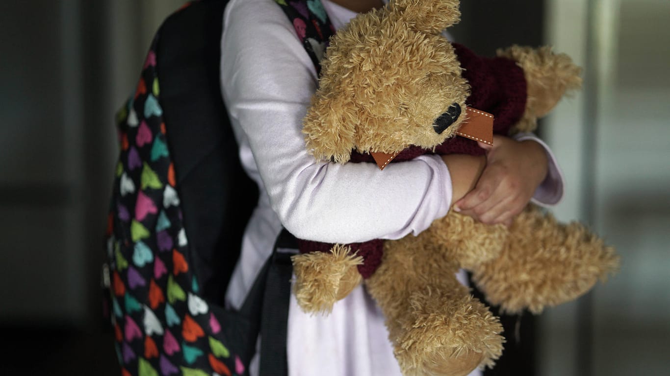 Ein junges Mädchen hält einen Stoffbären (Symbolbild): In einer Kita in Bonn gibt es einen ersten Corona-Fall.