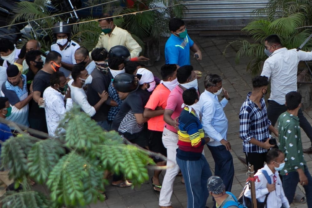 Indien, Mumbai: Ein Polizist in Zivil holt mit einem Schlagstock gegen die in einer Warteschlange stehenden Kunden eines Alkoholika-Ladens aus. Sie haben nicht den nötigen Abstand zueinander eingehalten.