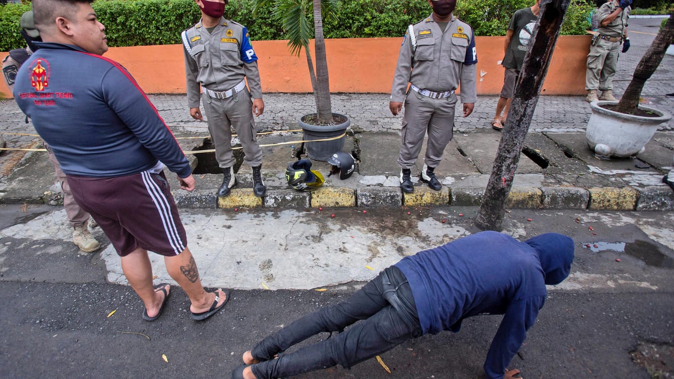 Indonesien, Medan: Ein Mann muss als Strafe gegen den Verstoß einer Maskenpflicht an öffentlichen Orten Liegestütze machen.