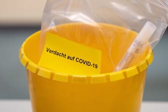 Ein Teströhrchen liegt in einer Tüte mit der Aufschrift "Verdacht auf COVID-19".