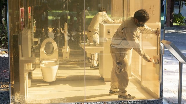 Ein Mann schließt die Tür einer neu installierten öffentlichen Toilette mit transparenten Wänden, die im Yoyogi Fukamachi Mini Park im Bezirk Shibuya steht. Ein Mann schließt die Tür einer neu installierten öffentlichen Toilette mit transparenten Wänden, die im Yoyogi Fukamachi Mini Park im Bezirk Shibuya steht.