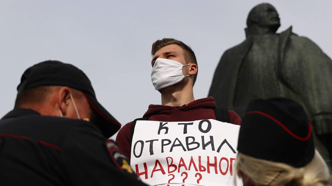 "Wer hat Nawalny vergiftet?", steht auf dem Plakat eines Mannes in der sibirischen Stadt Nowosibirsk. Vor ihm haben sich zwei Polizisten postiert.