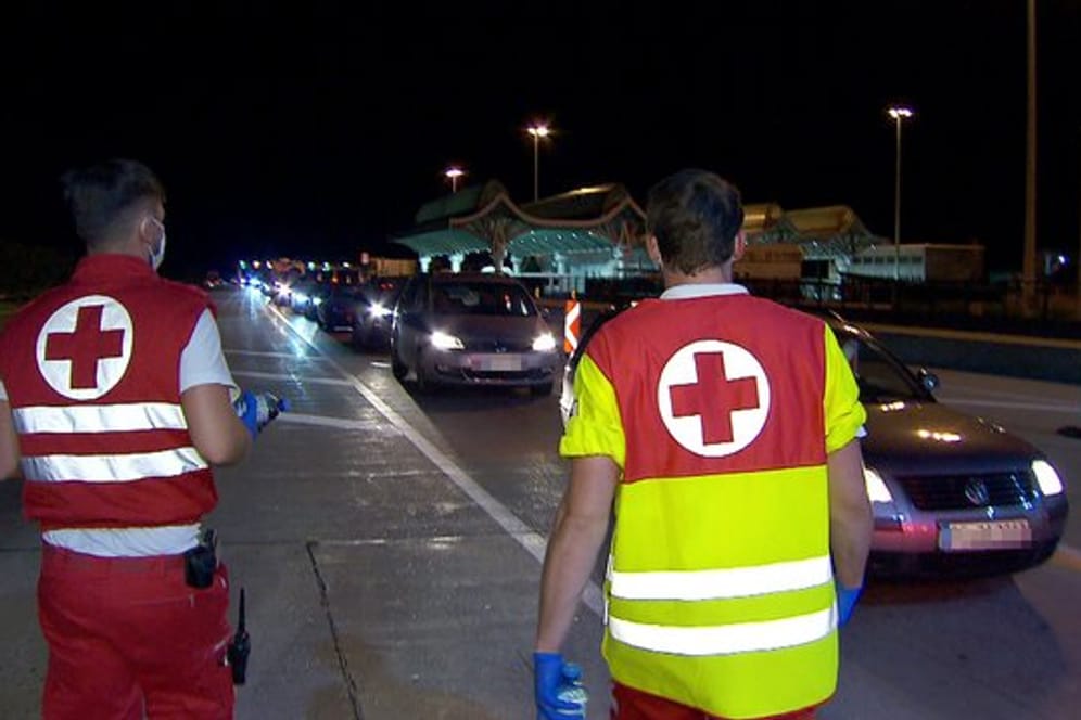 Mitarbeiter des Roten Kreuzes betreuen in der Nacht Autofahrer in einem kilometerlangen Stau bei der Einreise nach Österreich am Karawankentunnel.