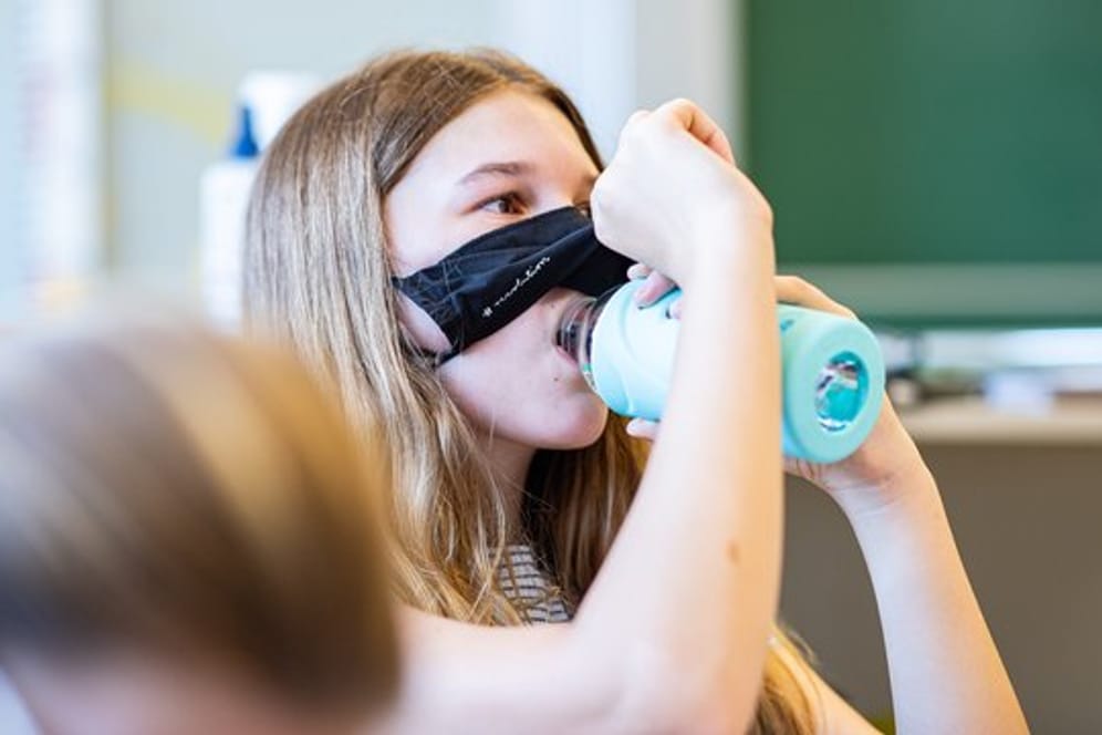 Eine Schülerin der Klasse 8a der Gesamtschule in Münster hebt ihre Mund- und Nasenmaske an, um etwas zu trinken.